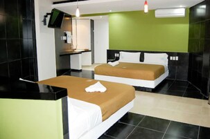 Habitación de hotel con dos camas, un escritorio, un televisor y una pared verde.