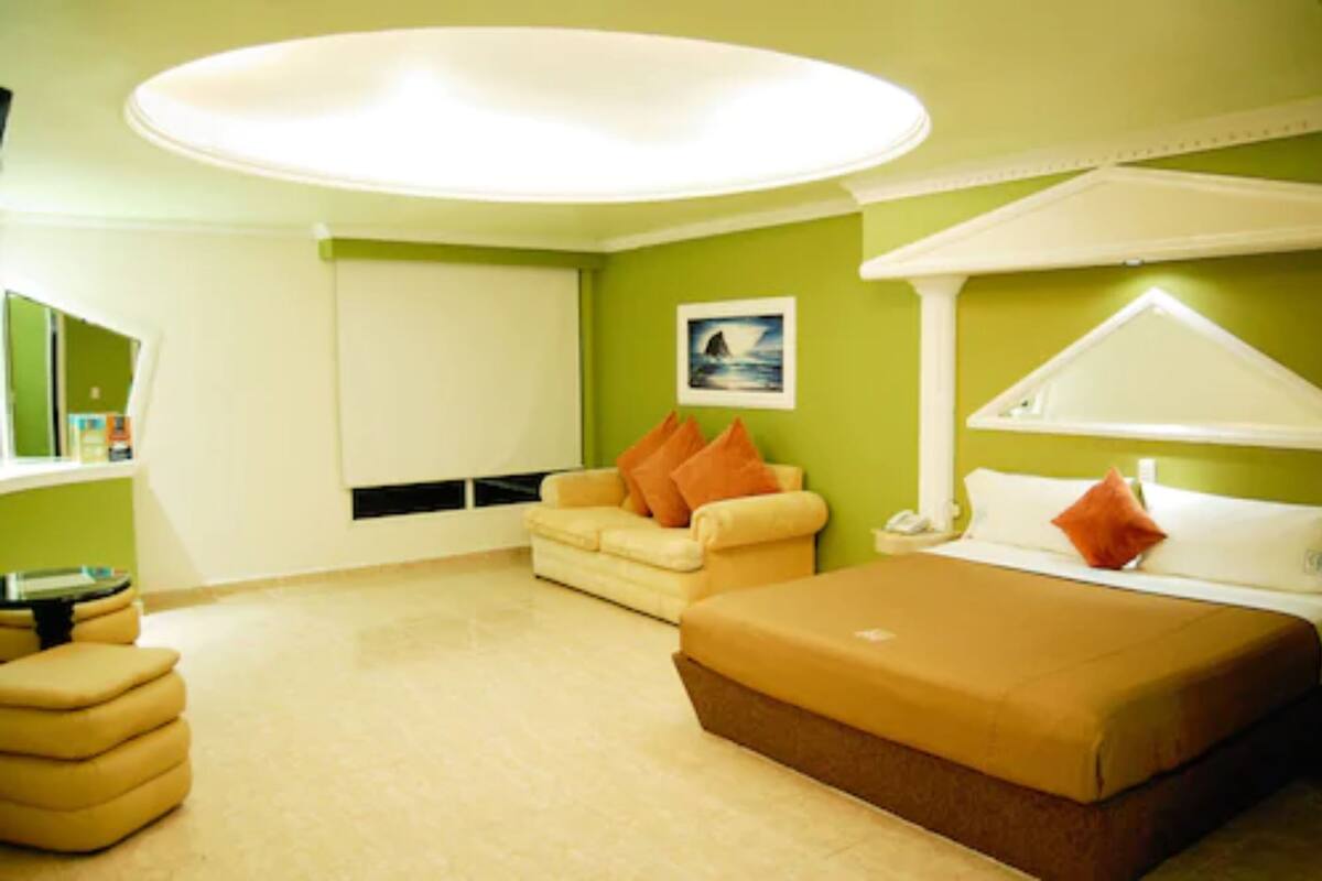 A room with a bed, a sofa, a small table, and a window.