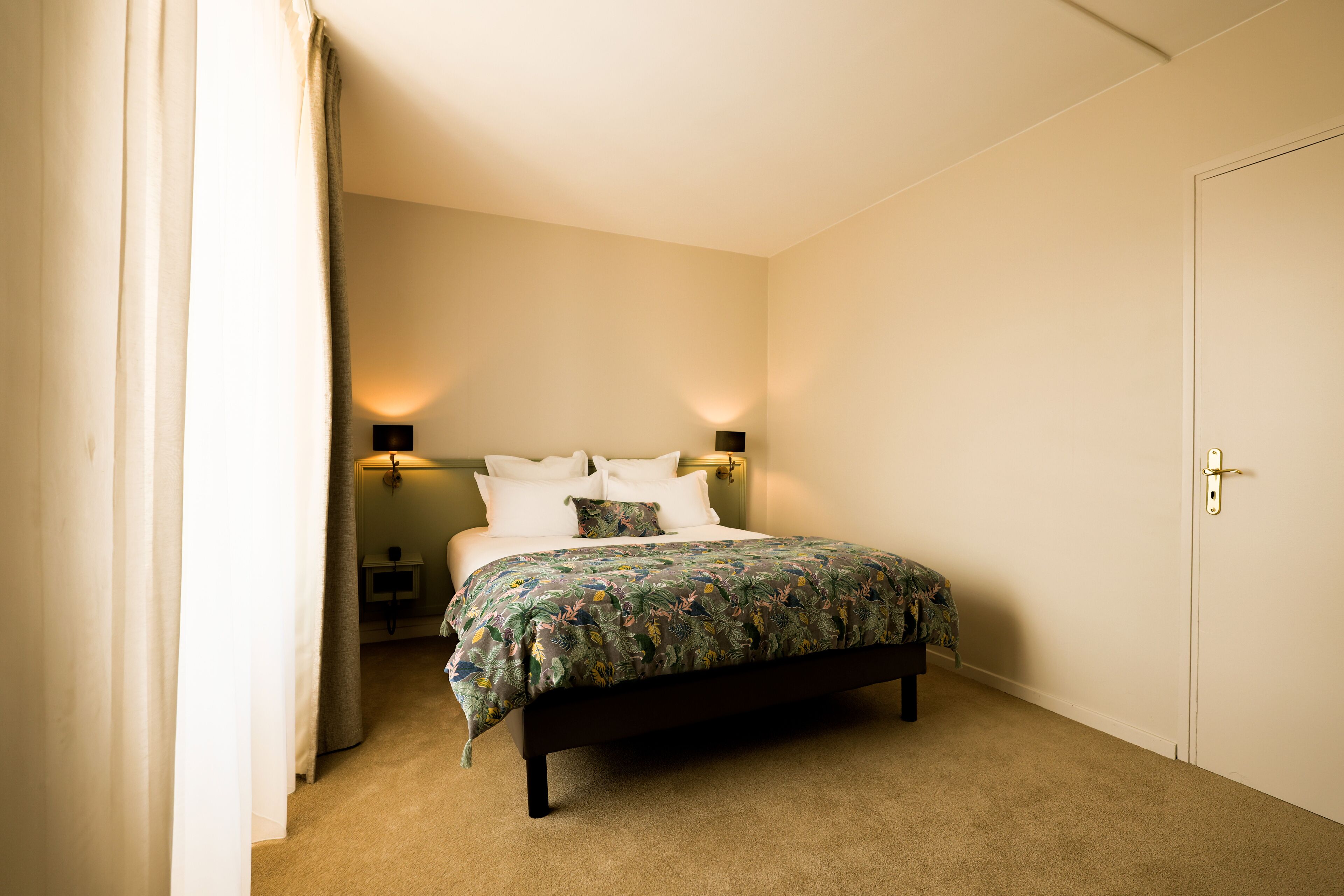 A bedroom with a bed, a nightstand, a lamp, and a door.