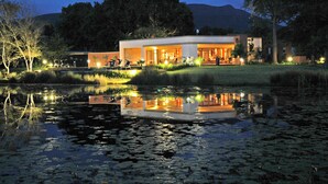 Un hotel moderno con piscina y zona de estar exterior, rodeado de árboles y una montaña al fondo.