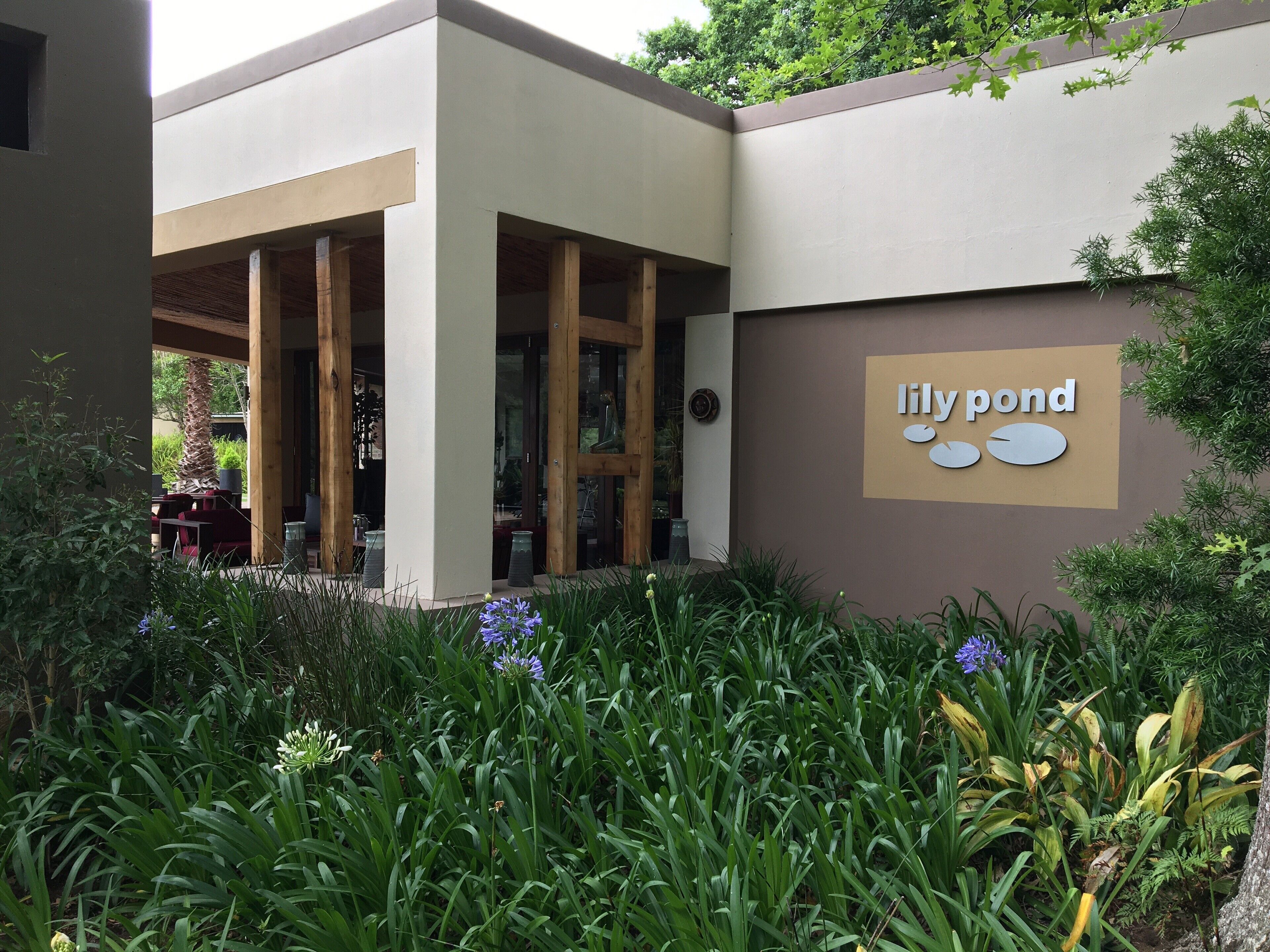 A building with a sign reading "lily pond" and a covered outdoor seating area with tables and chairs.