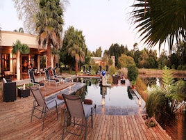 Una piscina al aire libre, sombrillas, sillones reclinables de piscina