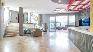En moderne lobby med trappe, siddeområde og reception.