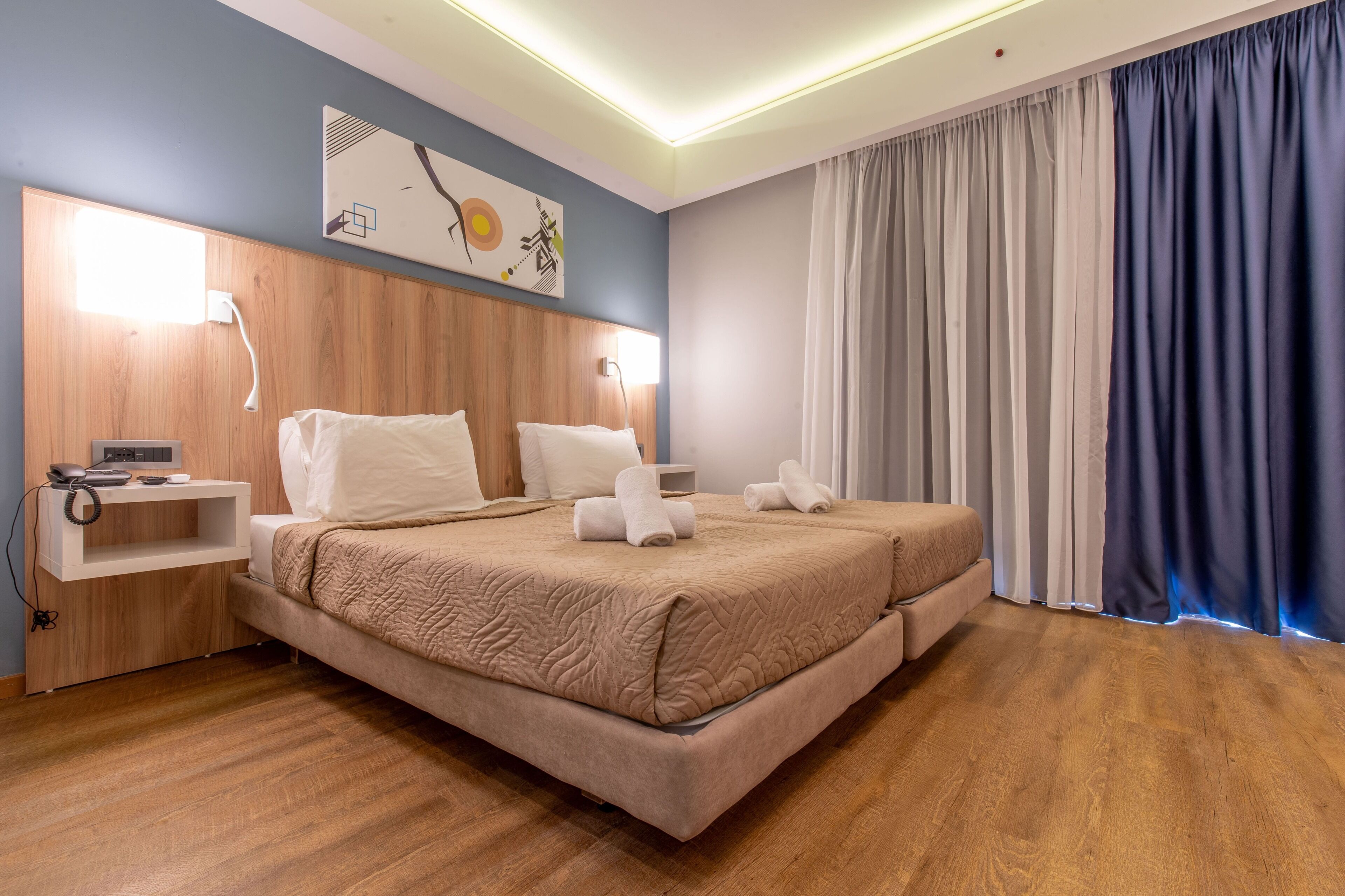A hotel room with a large bed, bedside tables, a desk, and a wall-mounted artwork.