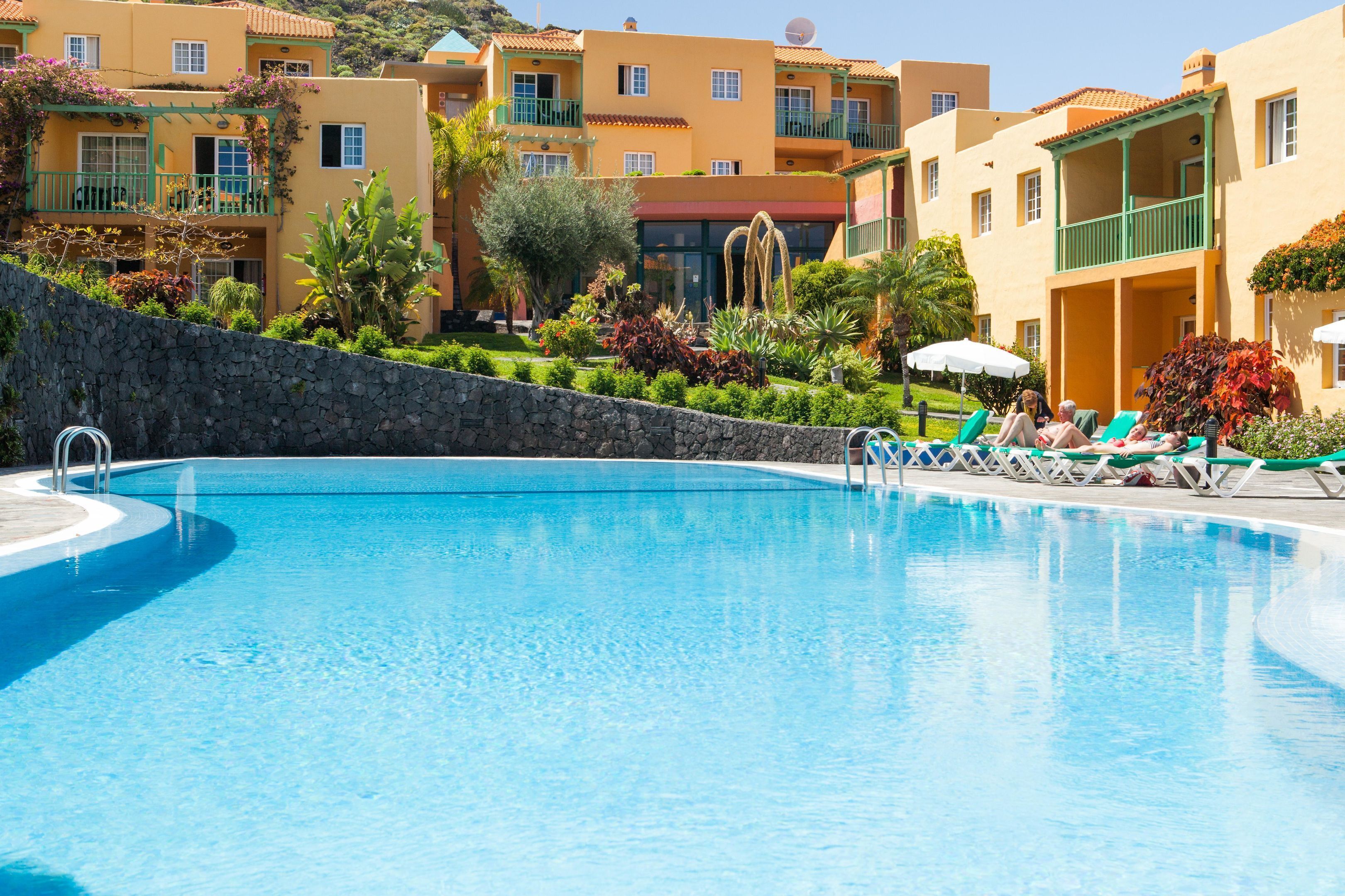 Una piscina con sillones de descanso y una pared de piedra.