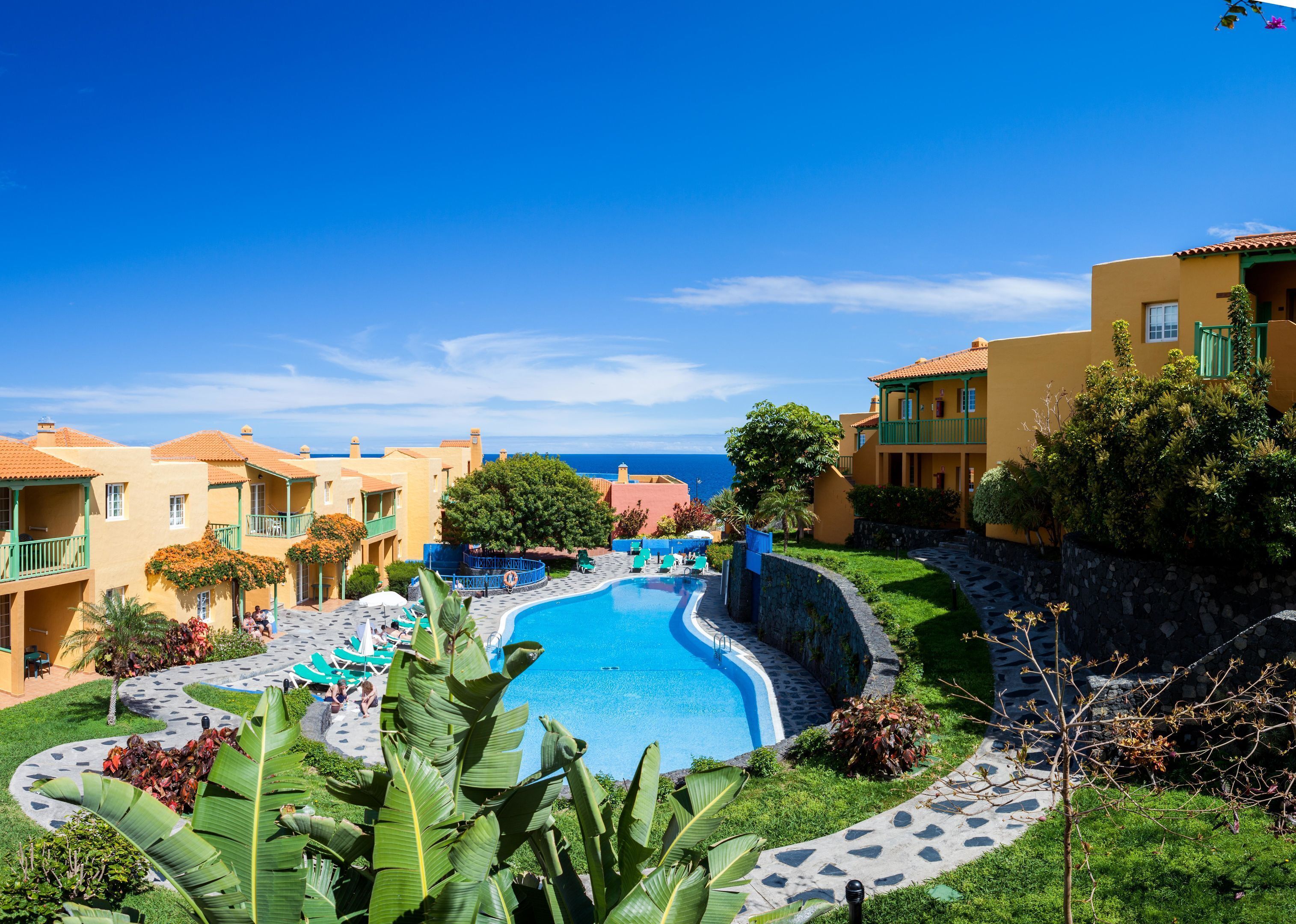Un complexe hôtelier doté d’une piscine, de plusieurs balcons et offrant une vue sur la mer.
