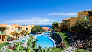 Un complexe hôtelier doté d’une piscine, de plusieurs balcons et offrant une vue sur la mer.