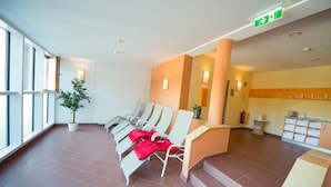 A waiting area with chairs, a plant, and a reception desk. - JUFA Hotel Planneralm (Irdning-Donnersbachtal)