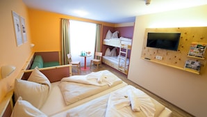 A hotel room with two beds, a TV, a small table, and a green sofa. - JUFA Hotel Planneralm (Irdning-Donnersbachtal)