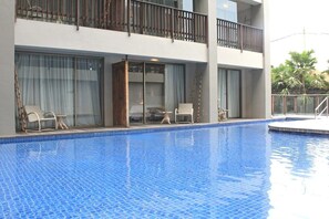 A hotel with a swimming pool, outdoor seating, and a balcony. - Four Points By Sheraton Bali, Kuta (Kuta)