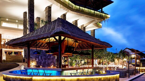 An outdoor bar area with a pool, seating, and a thatched-roof structure. - Four Points By Sheraton Bali, Kuta (Kuta)