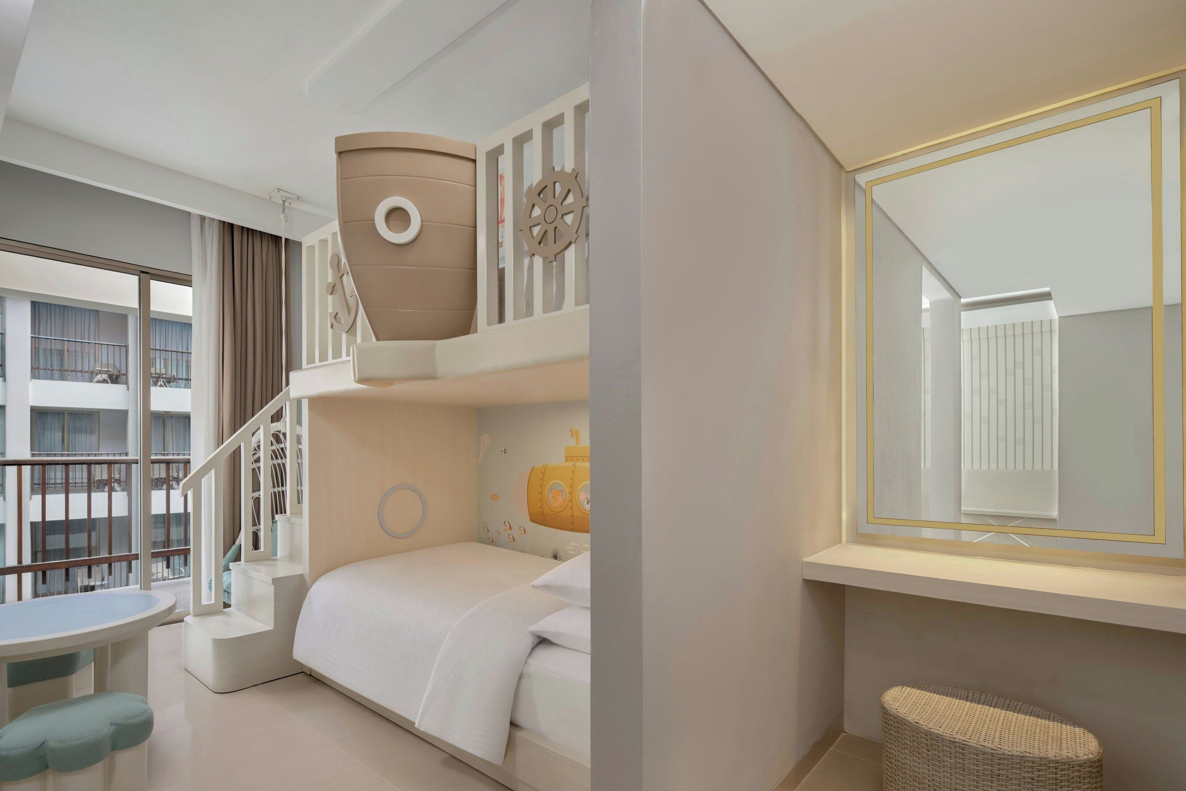 A modern hotel room with a bunk bed, a small table, and a window with a view of other buildings.
