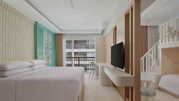 Een moderne hotelkamer met een groot bed, een bureau met een flatscreen-televisie, een klein tafeltje en een balkon met een hekwerk.
