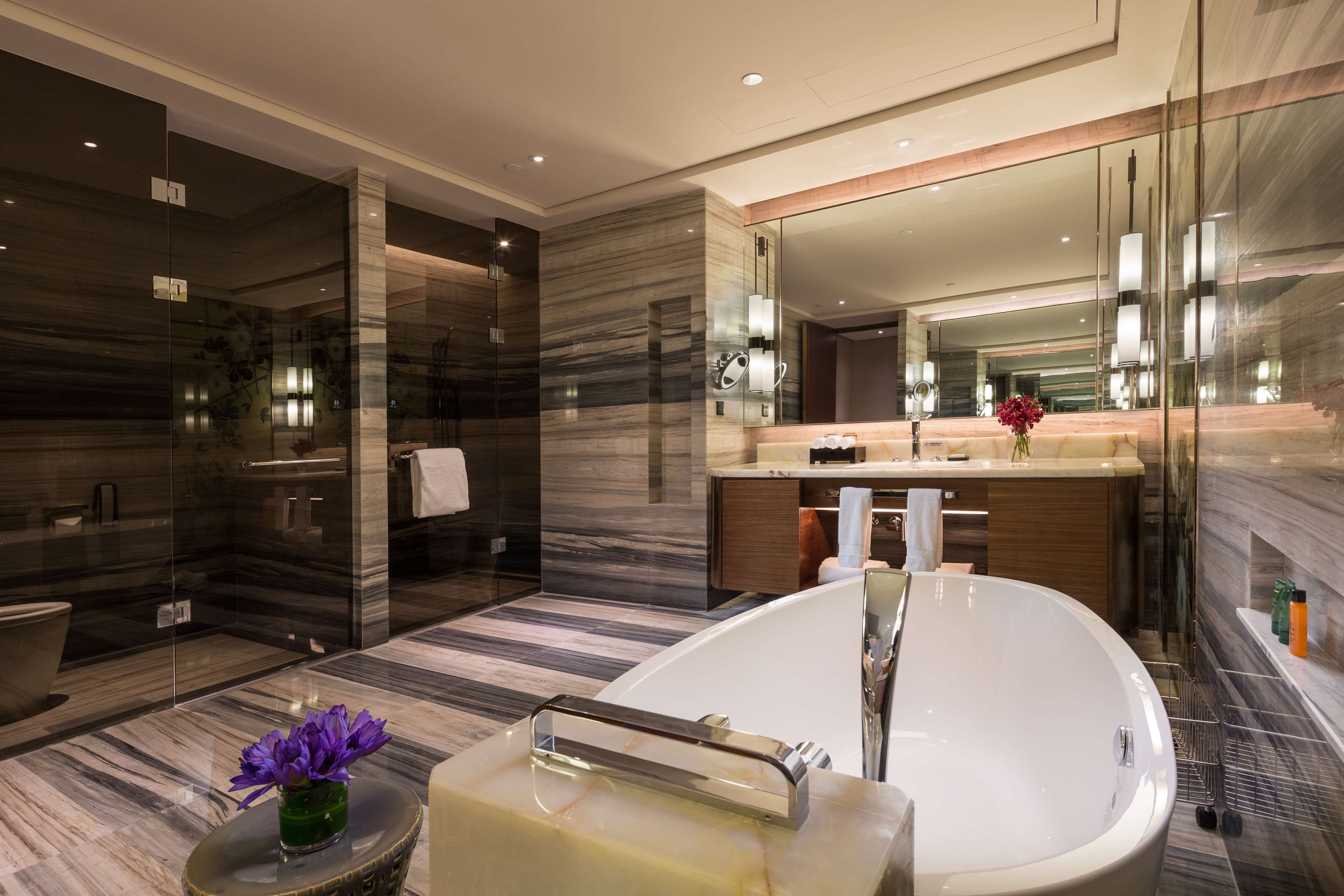 A modern bathroom with a freestanding bathtub, a glass shower enclosure, and a vanity with a large mirror.