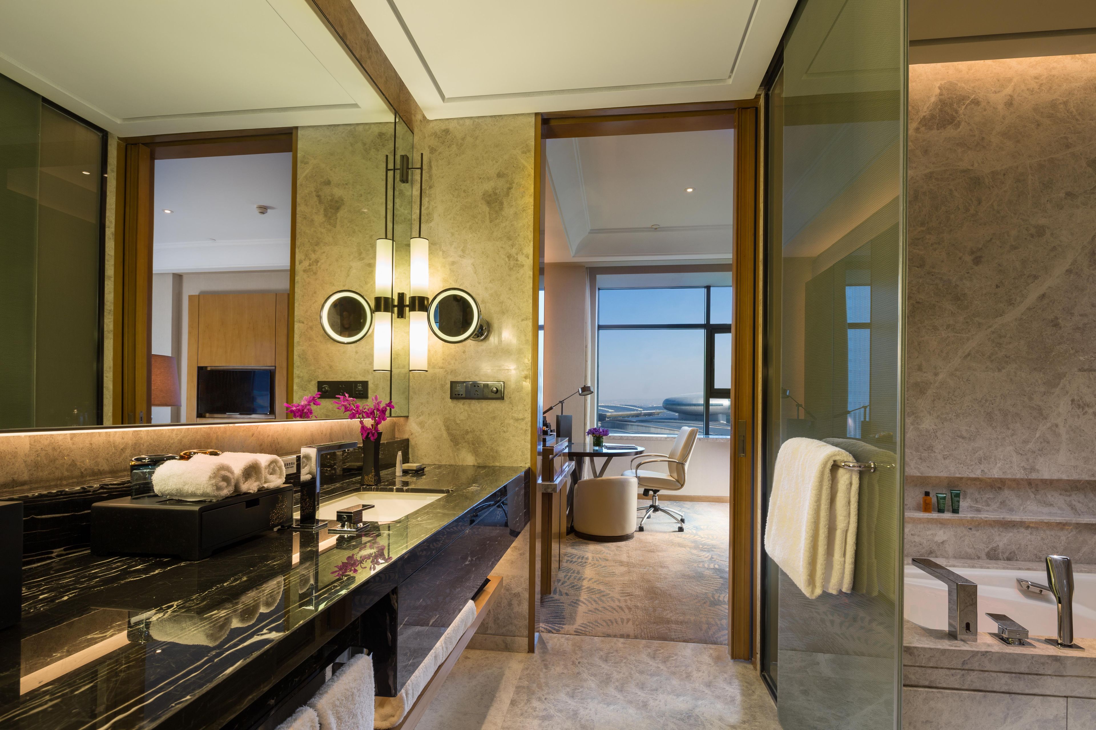 Un baño moderno con un espejo grande, lavamanos dobles y tocador.