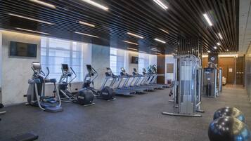 Une salle de sport équipée de tapis de course, de vélos elliptiques et de ballons d’exercice.