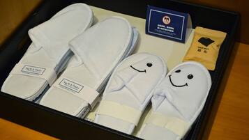 A box containing slippers with smiley faces, a shoe mitt, and a card with a no-smoking symbol.