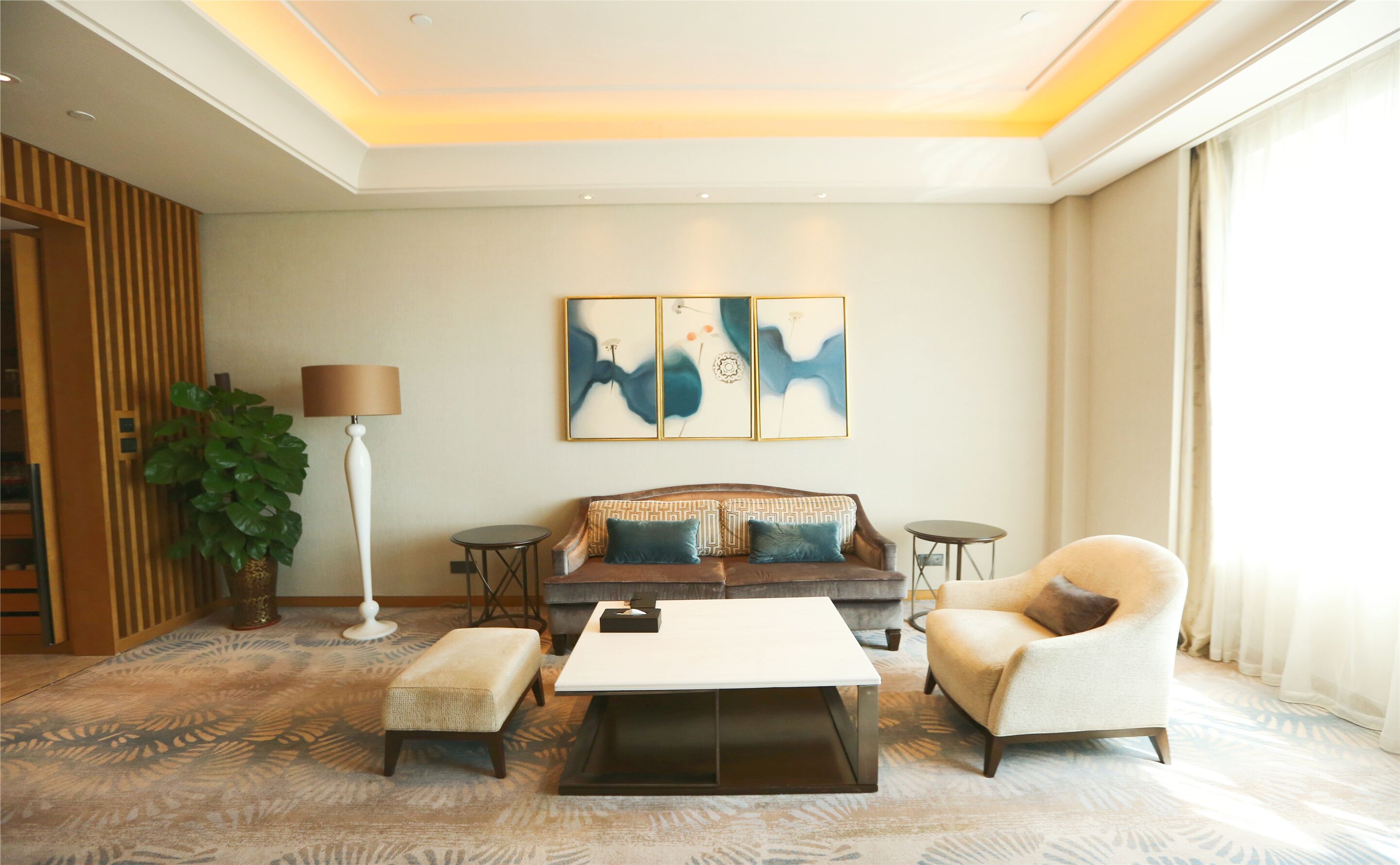A modern living room with a sofa, two armchairs, a coffee table, a floor lamp, and abstract wall art.