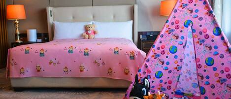 A hotel room with a bed, a teddy bear, a drum, and a tent.