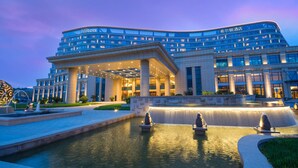 A modern hotel with a curved facade, a spacious entrance, and a central water feature. - Hilton Urumqi (Ürümqi)