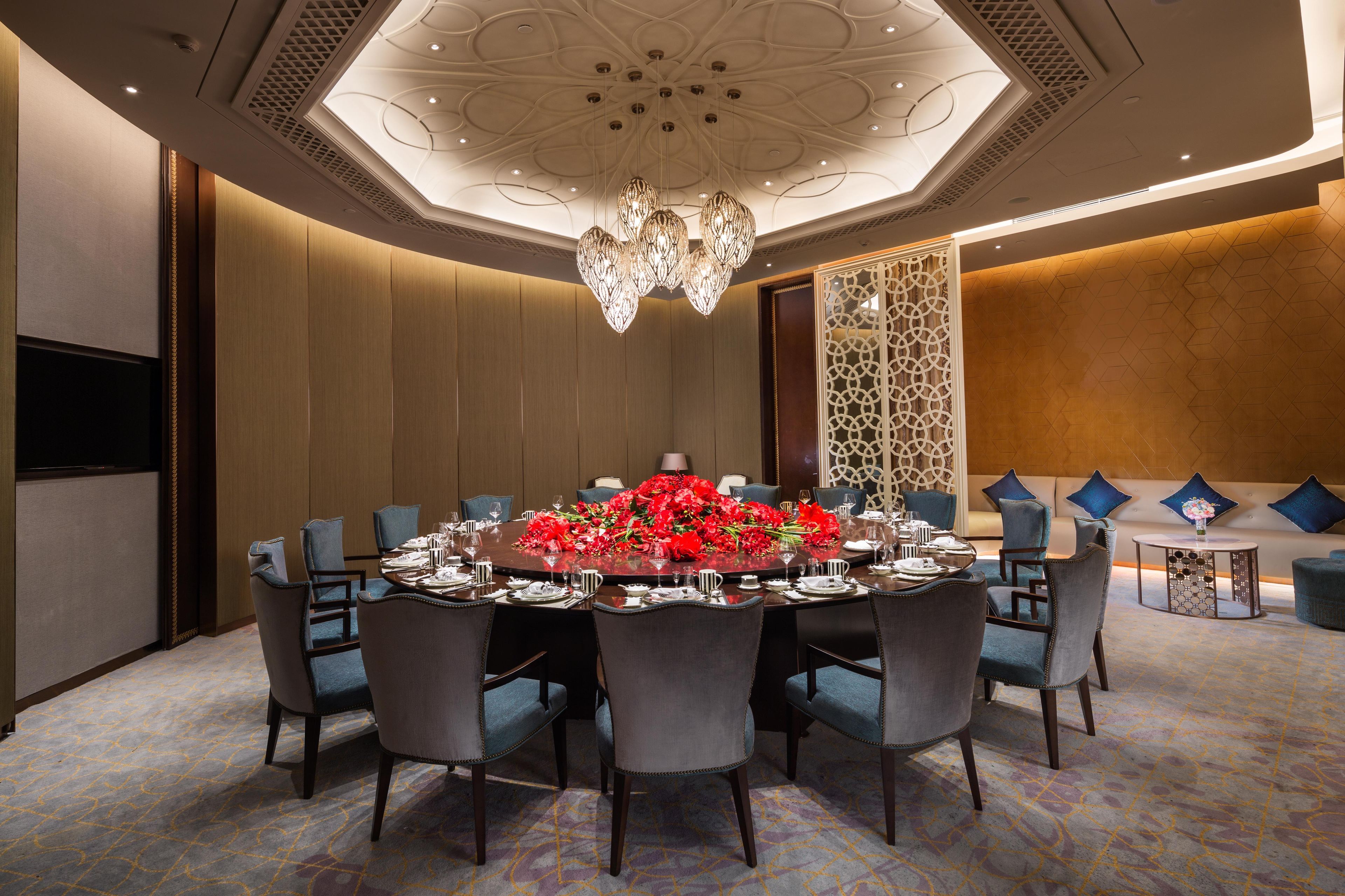 A conference room with a round table, chairs, and a chandelier.