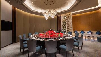 A conference room with a round table, chairs, and a chandelier.