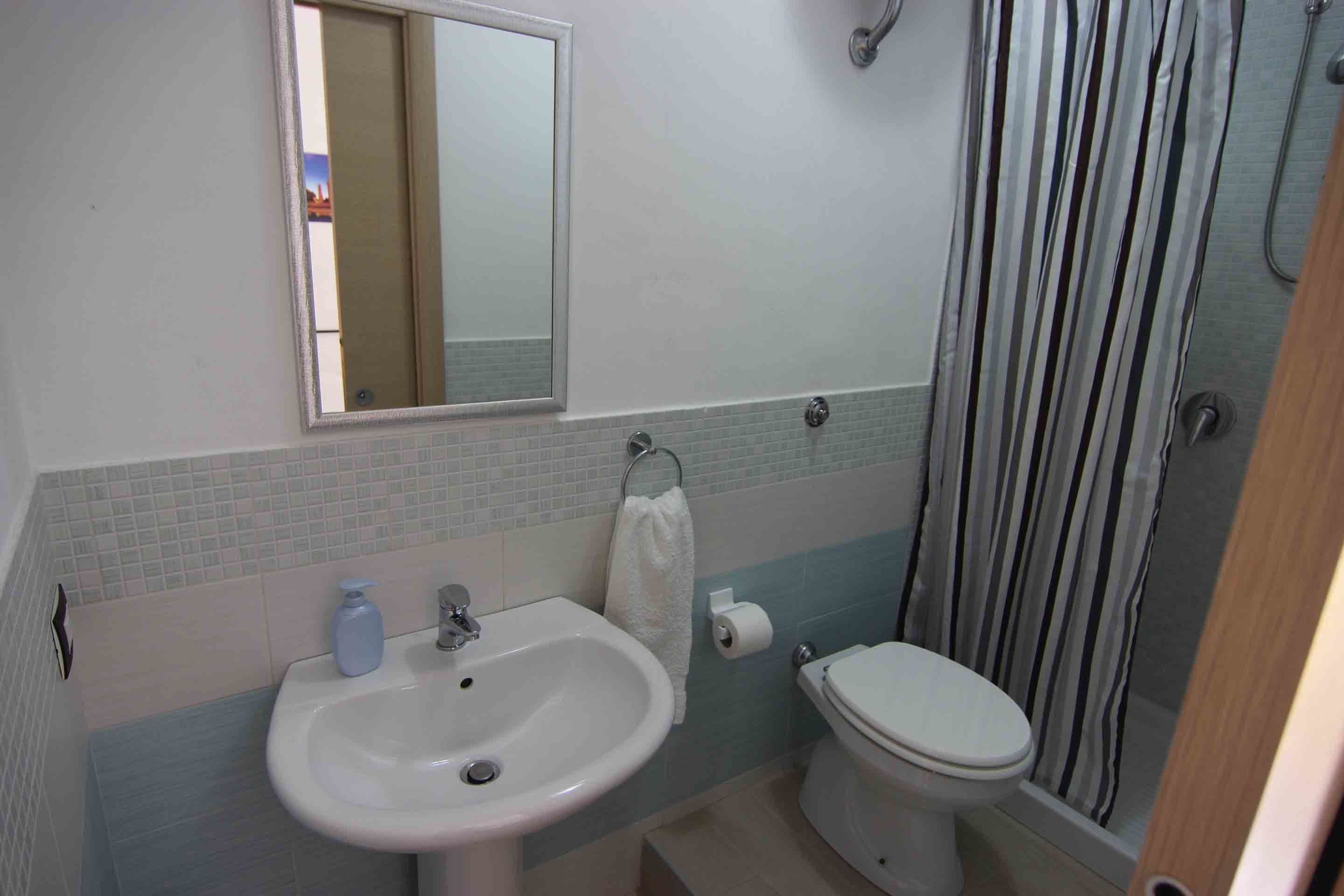 A bathroom with a sink, mirror, toilet, and shower curtain.