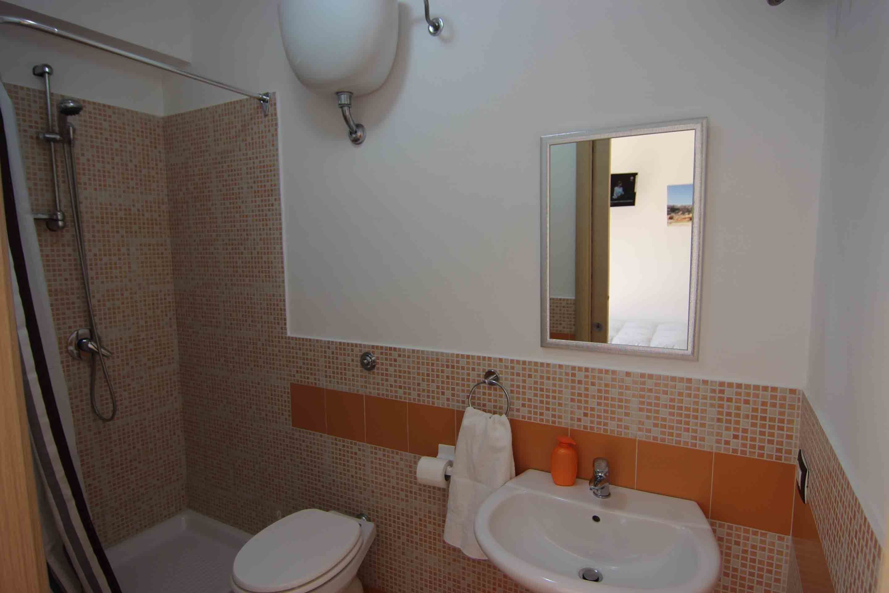 Un bagno con doccia, WC e lavandino.