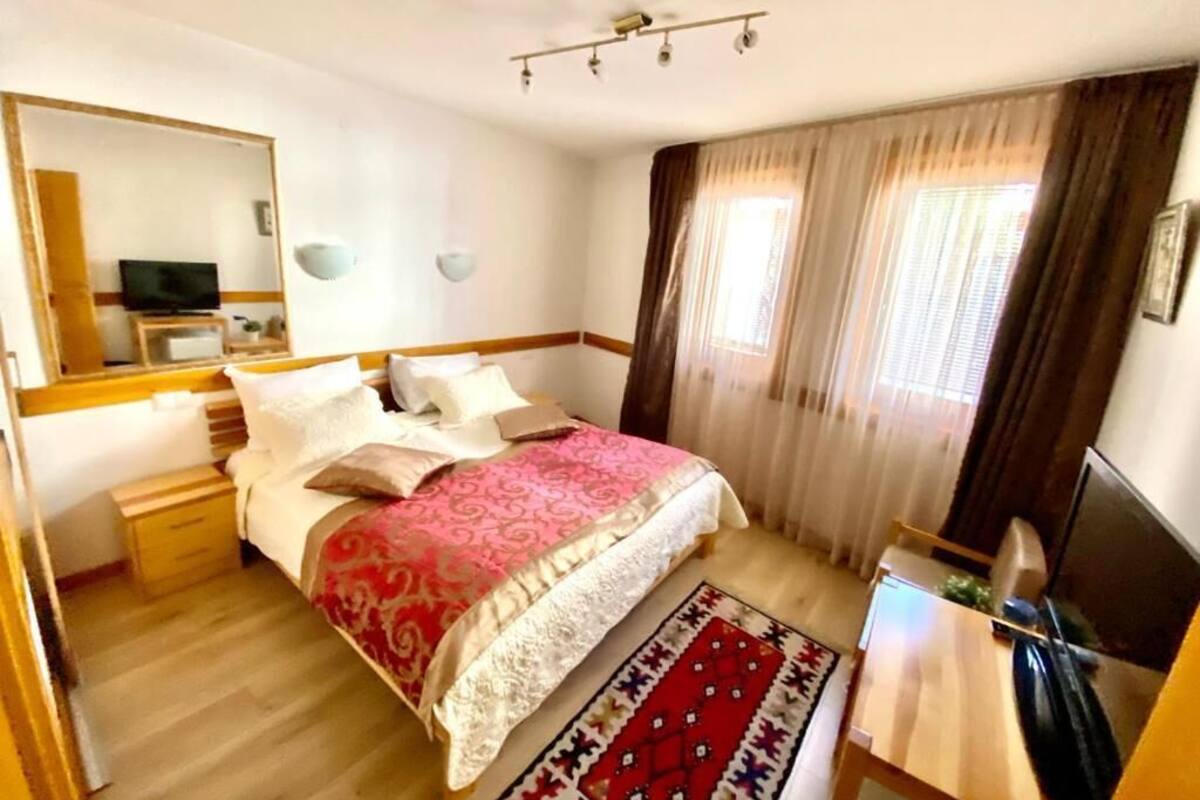 A bedroom with a bed, bedside table, TV, and a mirror.
