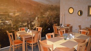 Un espace repas avec des tables et des chaises en bois, une fresque représentant un paysage urbain sur le mur, et deux miroirs encadrés.