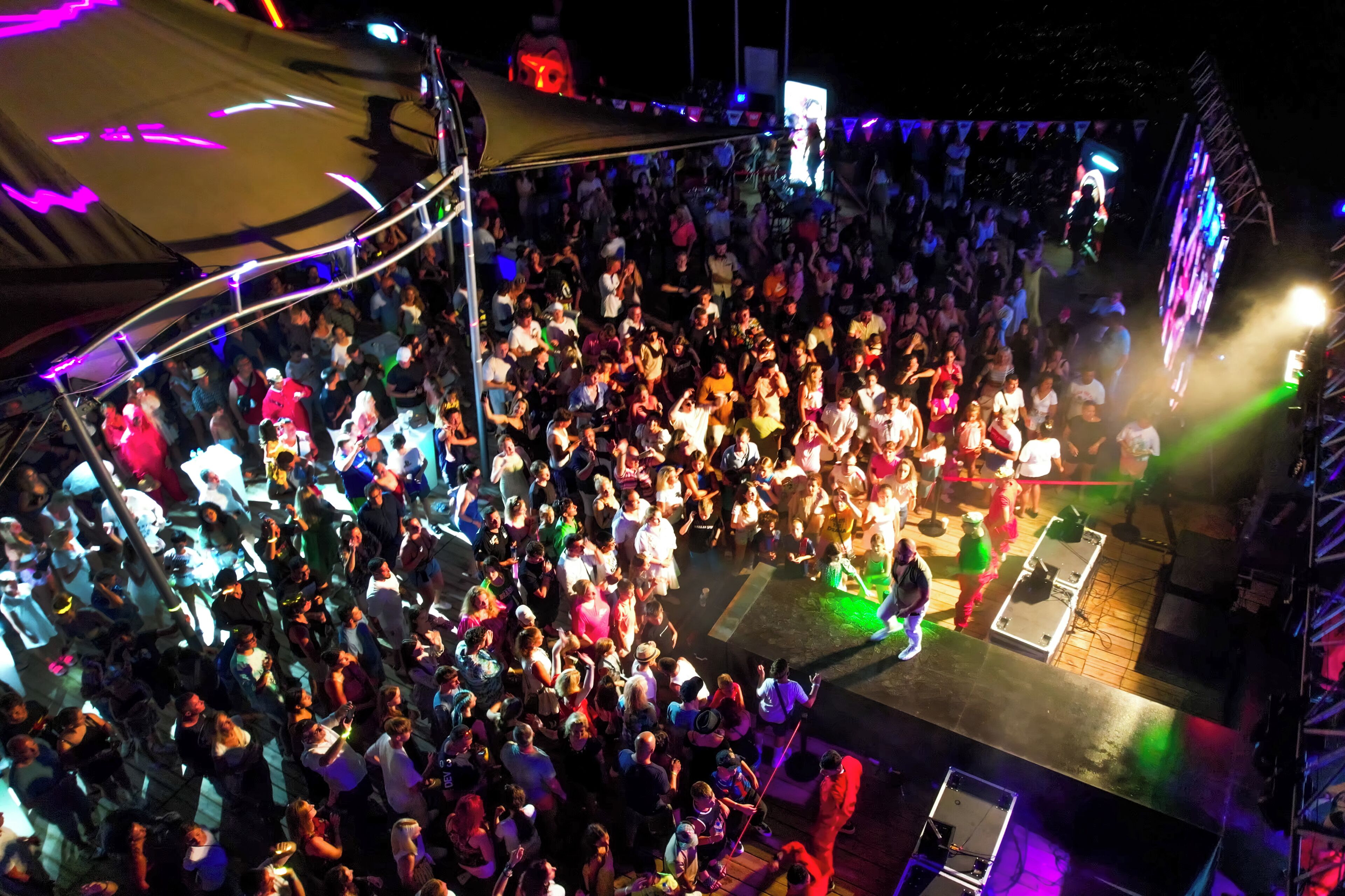 A crowded outdoor event with a stage and a large audience.