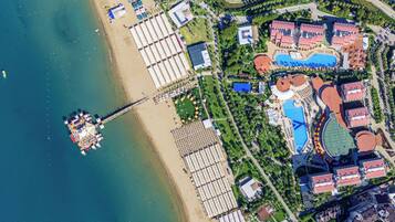 Vista aérea de un resort con playa, un muelle y varias edificaciones con techos rojos.