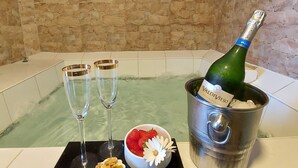 Una bañera con una botella de champán, dos copas y un bol de fresas y nueces.