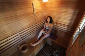 A sauna with wooden walls and benches, a small window, and a towel rack. - Hotel Lodge Las Cascadas (Puerto Octay)