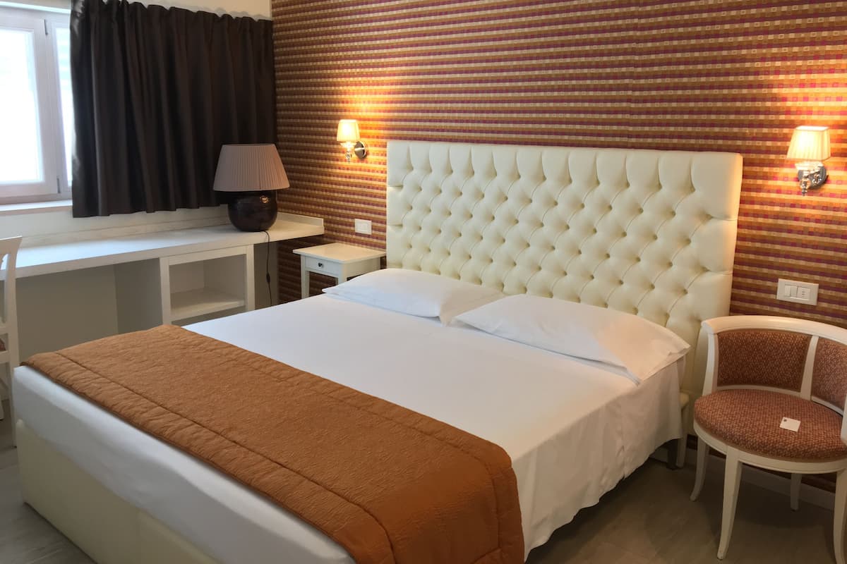Habitación de hotel con una cama grande, un escritorio, una silla y una pared con diseño de cuadros.