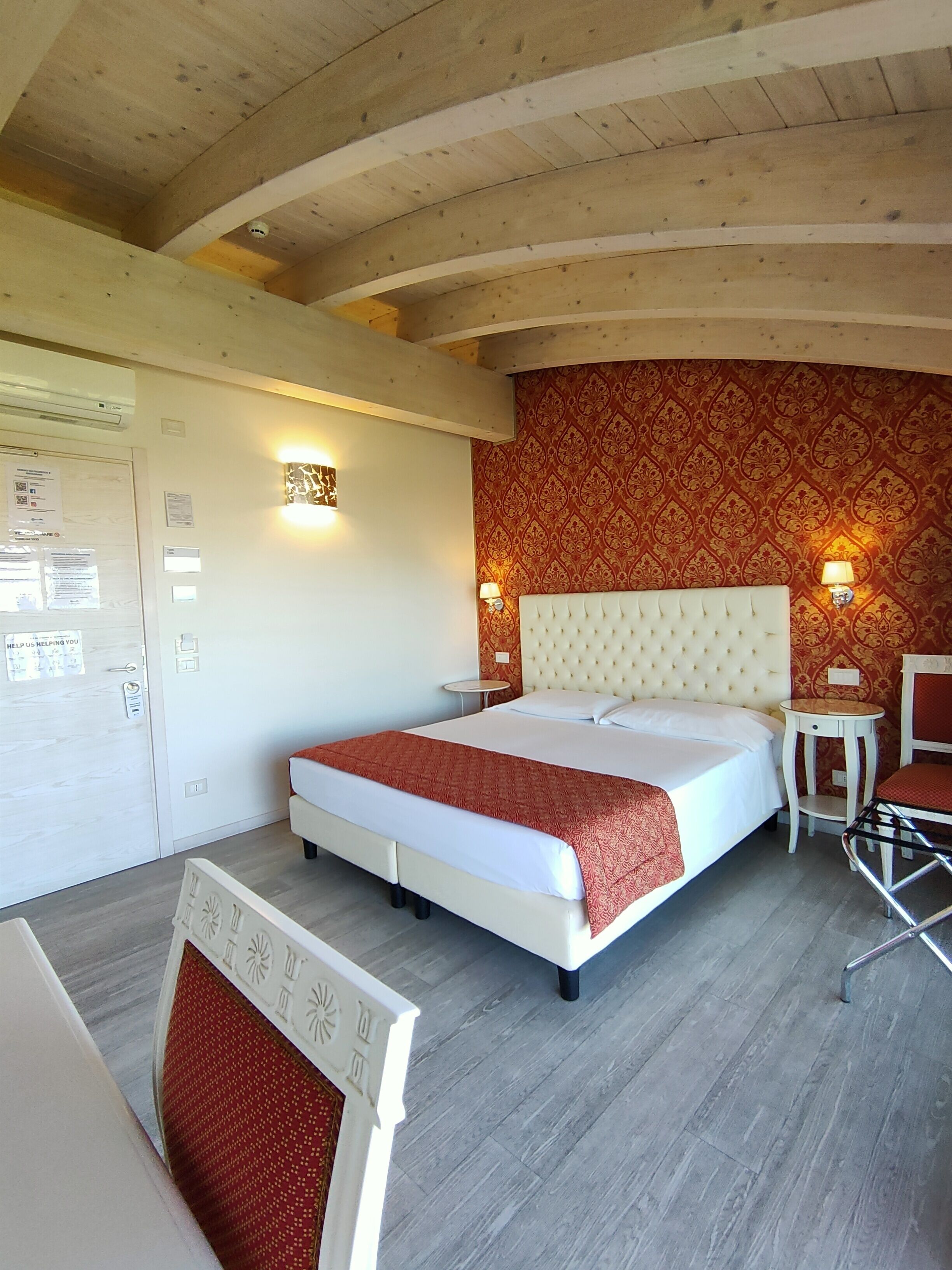 Ein Schlafzimmer mit einem großen Bett, zwei Nachttischen, einem Sessel und einer Holzbalkendecke.