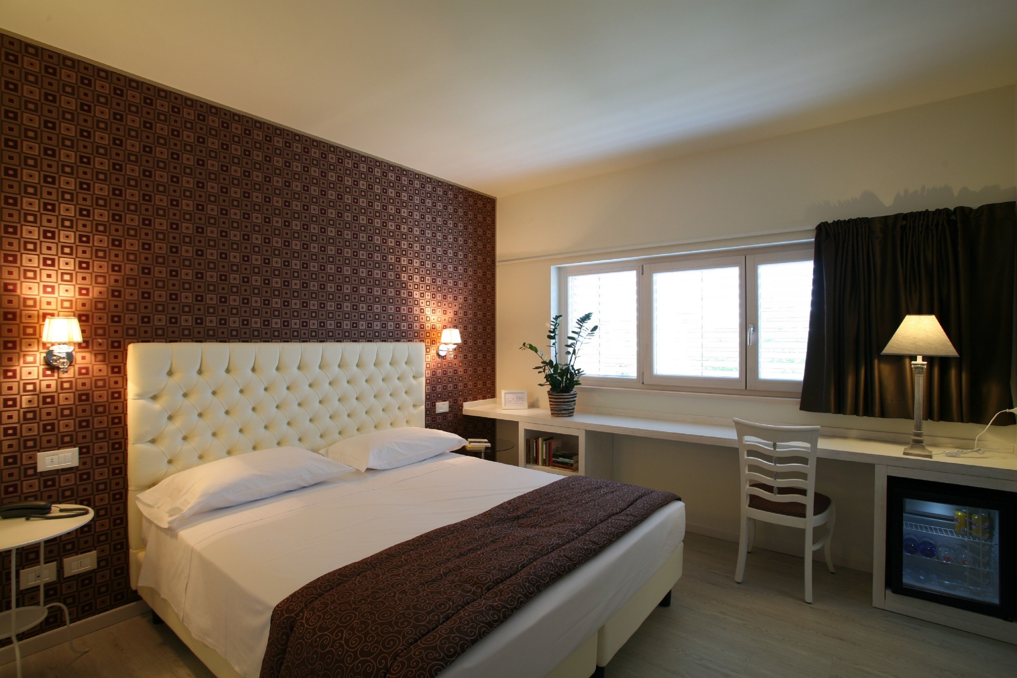 Ein Hotelzimmer mit einem großen Bett, einem Schreibtisch, einem Stuhl und einem kleinen Kühlschrank.