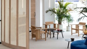 A modern living room with a wooden partition, a blue sofa, and a large potted plant. - Barcarola Club (Tías)