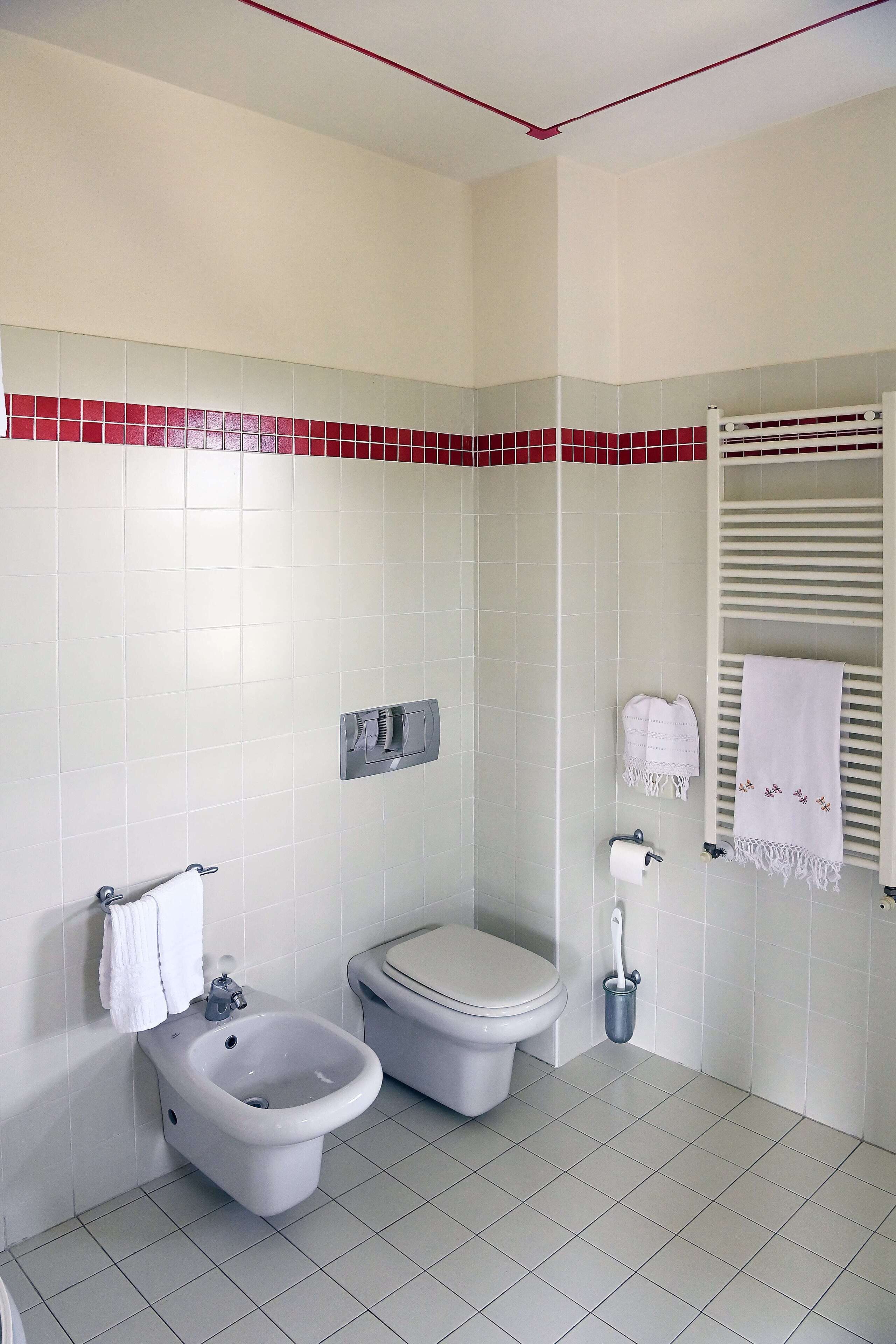 Un baño con bidé, inodoro y perchero para toallas.