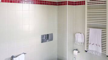 Un baño con bidé, inodoro y perchero para toallas.