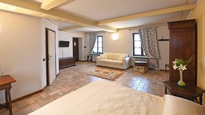 Een kamer met een bed, een bank, een houten kast en een radiator.