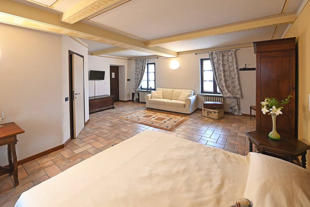 Une pièce comprenant un lit, un canapé, une armoire en bois et un radiateur.