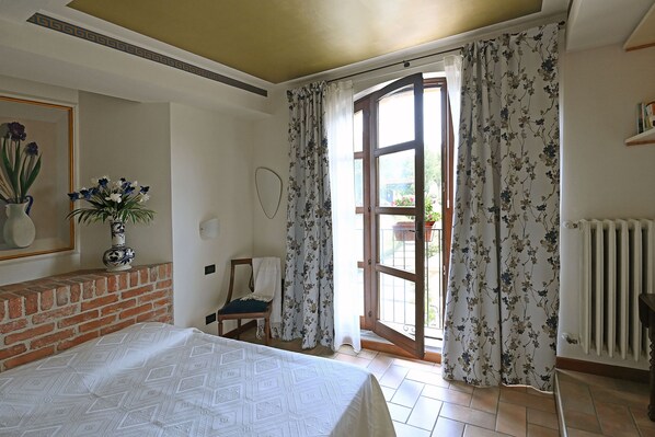 A room with a bed, a chair, a radiator, and a window with floral curtains.