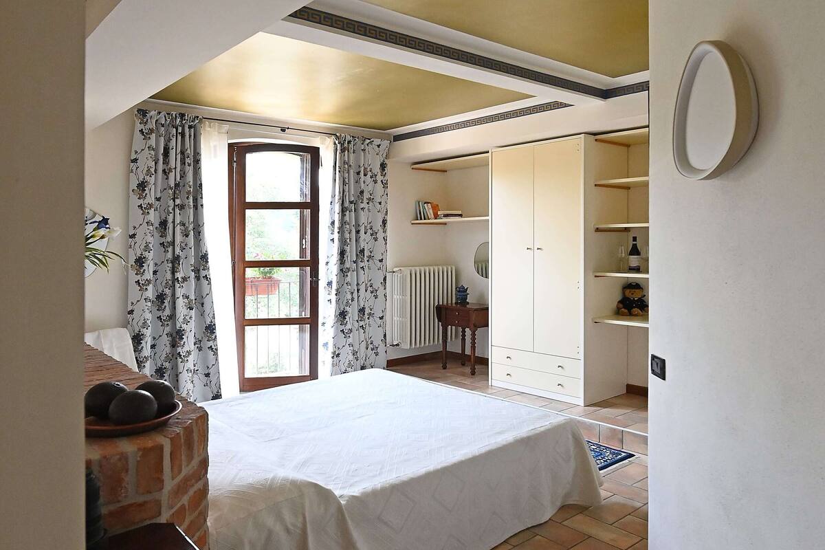 Une chambre à coucher avec un grand lit, une armoire, un radiateur et une petite table sur laquelle se trouve un panier de fruits.