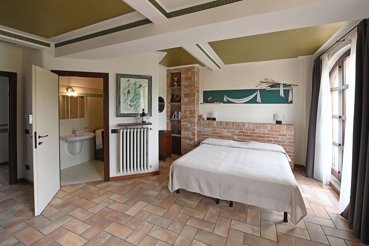 Une chambre avec un lit, une salle de bain avec un lavabo et un mur en briques.