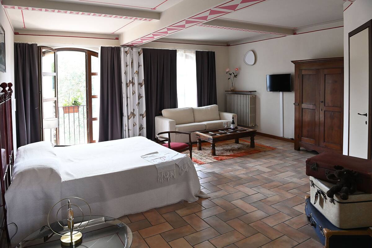 Une chambre d’hôtel comprenant un lit, un canapé, une table basse, une télévision et une armoire.