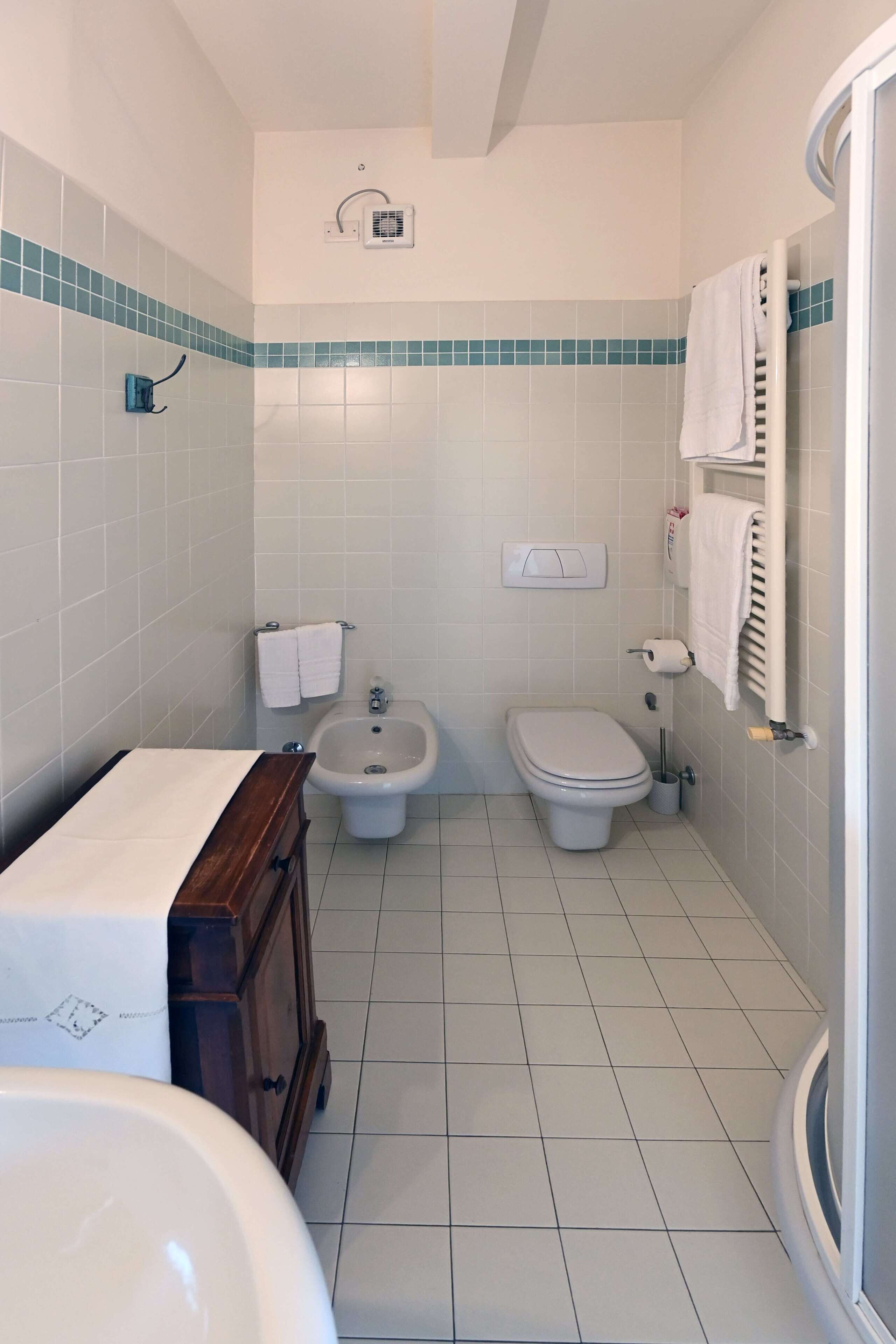 A bathroom with a bidet, toilet, and sink.