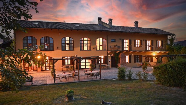 Een gebouw met twee verdiepingen, voorzien van een binnenplaats, gebogen ramen en een overdekt terras.