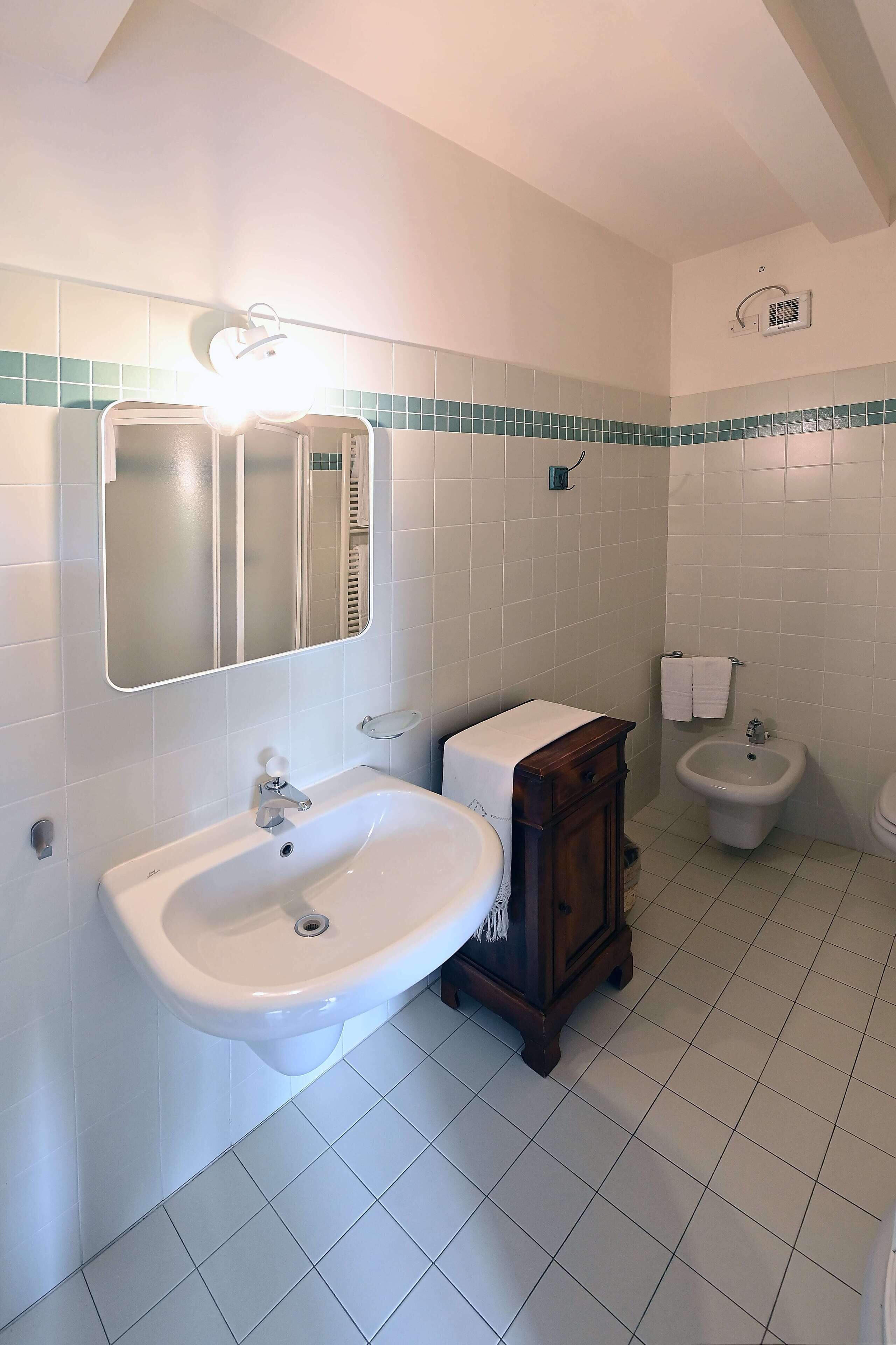 Un baño con lavabo, espejo, bidé y paredes de azulejos.