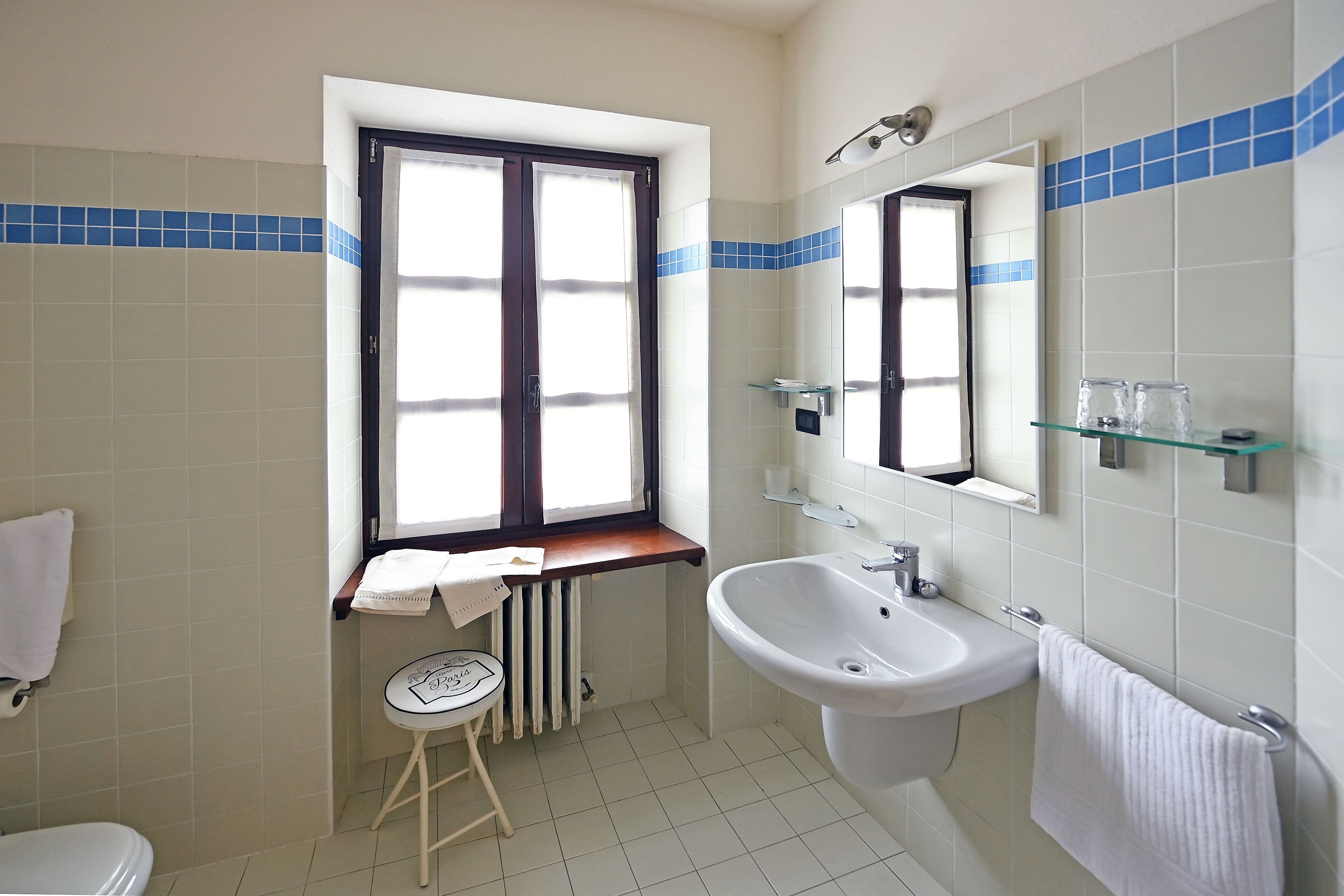 A bathroom with a toilet, sink, and window.